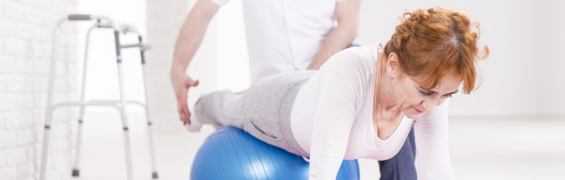 Ältere Frau bekommt Übungen auf dem Gymnastikball vorgezeigt